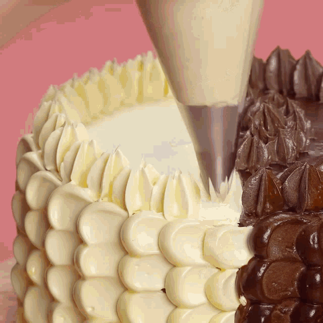 a cake with white frosting and chocolate frosting being frosted