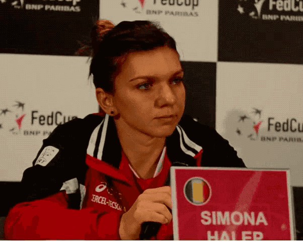 a woman sitting at a table with a sign that says simona halep
