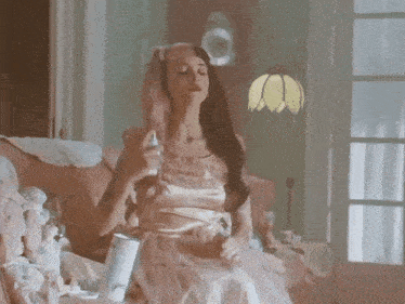 a woman in a pink dress is spraying perfume on her face
