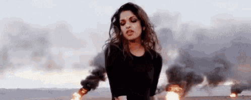 a woman is standing in a field with smoke coming out of it .