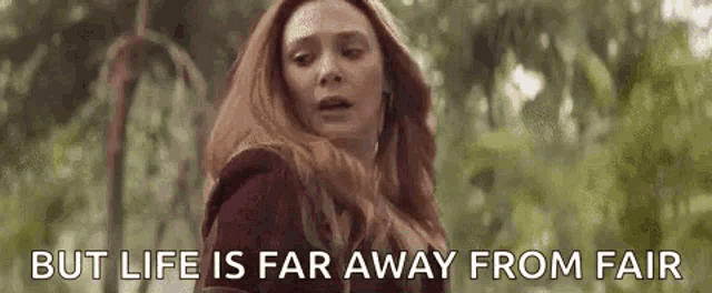 a woman with red hair is standing in a forest with the words `` but life is far away from fair '' written on the screen .