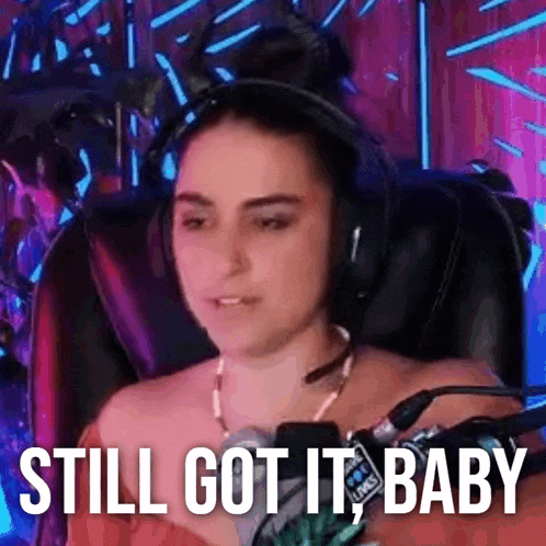a woman wearing headphones is sitting in a chair with the words `` still got it baby '' .