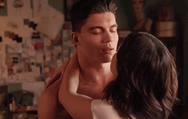 a man and woman are kissing in a room .