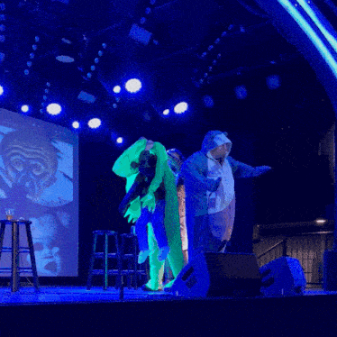 a group of people standing on a stage in front of a large screen