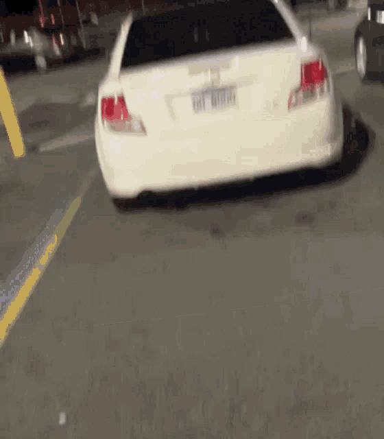 a white car is driving down a street with a license plate that starts with the letter e