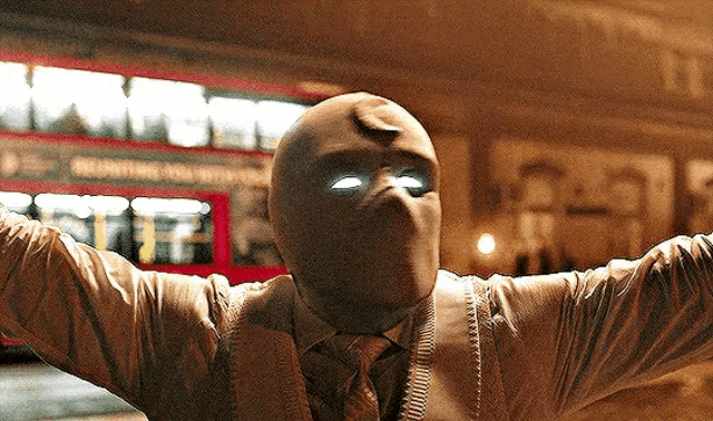a man wearing a mask with glowing eyes is standing in front of a bus .