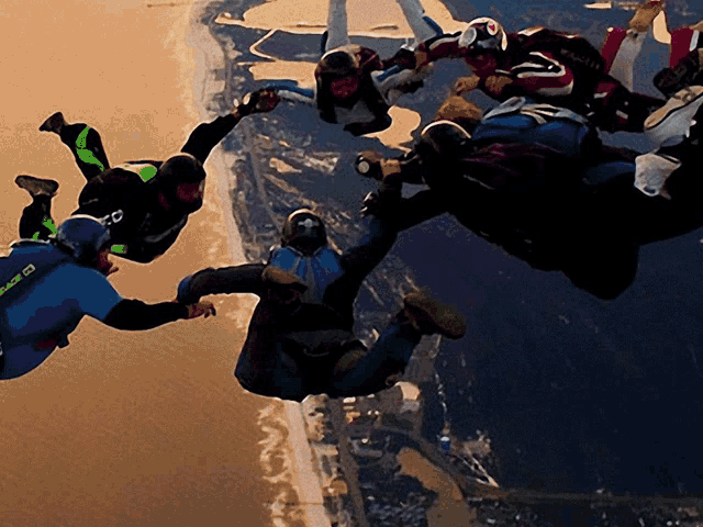 a group of people are flying through the air and one of them is wearing a blue shirt that says ' sd ' on it