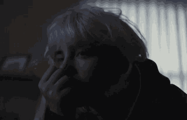 a woman with blonde hair is covering her face with her hand
