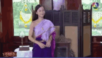 a woman in a purple dress is standing in front of a window