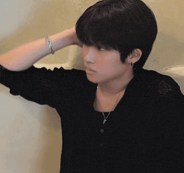 a young man wearing a black shirt and a necklace