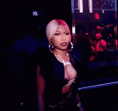 a woman is standing in a dark room wearing a very revealing top and earrings .