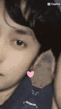 a close up of a man 's face with a pink heart on his ear