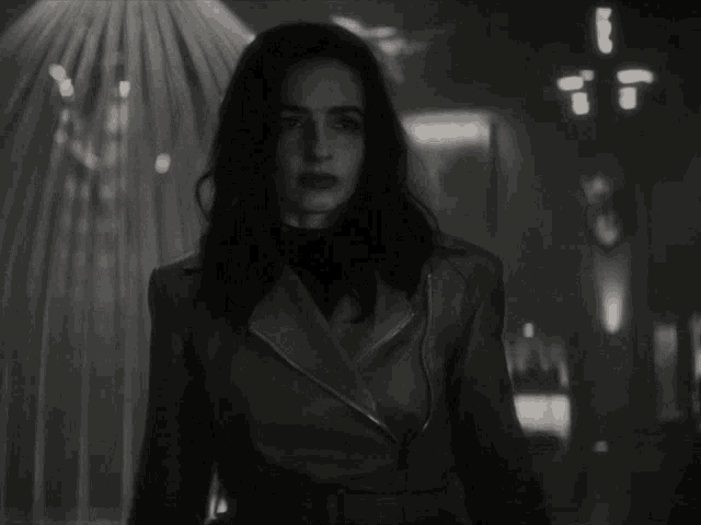 a black and white photo of a woman in a leather jacket and turtleneck