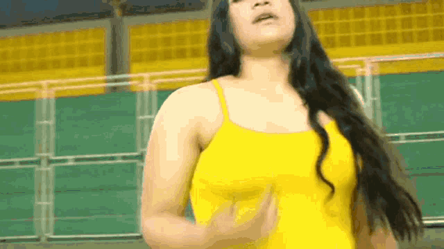 a woman in a yellow tank top is dancing