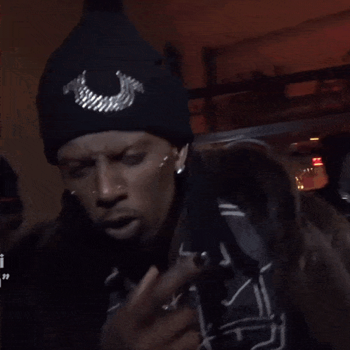 a man wearing a true religion beanie shows his middle finger