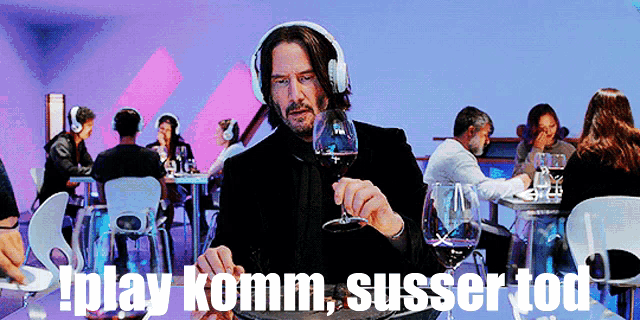 a man wearing headphones is holding a glass of wine in a restaurant with the words play komm susser tod below him