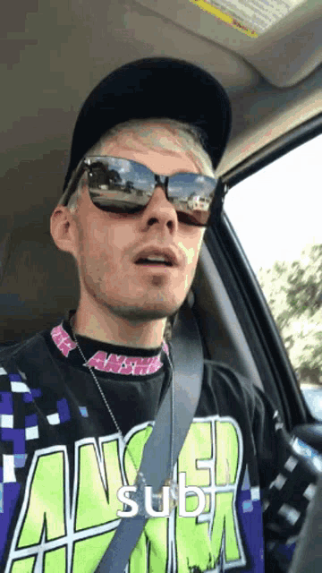 a man in a car wearing sunglasses and a shirt that says fangirl