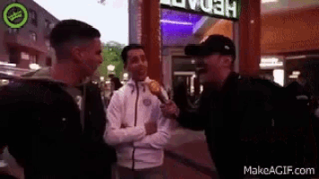 a man is holding a microphone and talking to two men .