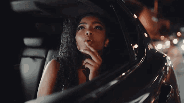 a woman is looking out the window of a car at night