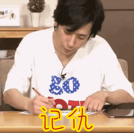 a man is writing on a piece of paper while wearing a shirt that says 80 on it .