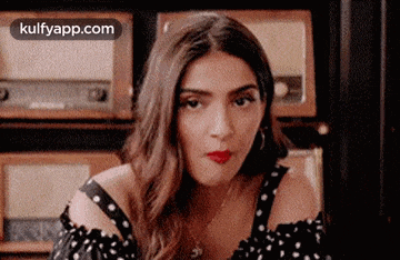 a woman in a black and white polka dot dress is sitting in front of a radio .