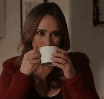 a woman is drinking a cup of coffee from a white cup .