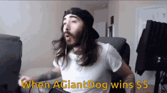a man with long hair and a beard is sitting in front of a computer with the words " when agiantdog wins $ 5 "