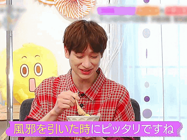 a man in a plaid shirt is eating with chopsticks