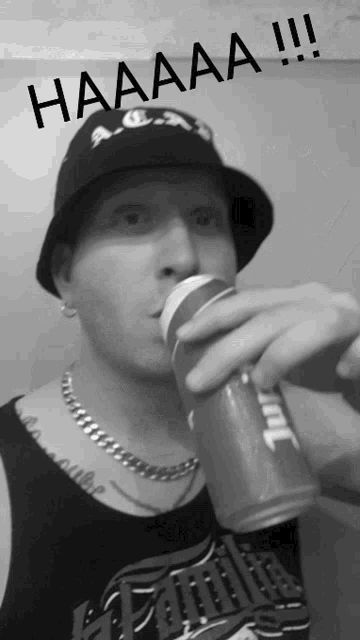a man wearing a hat and a tank top drinking from a can with haaaa written above him