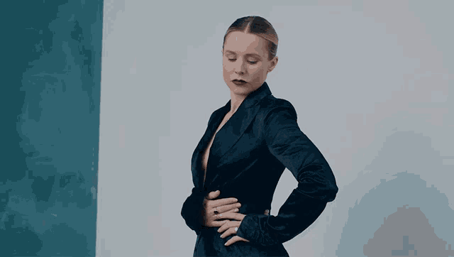 a woman in a black suit with a ring on her finger is standing with her hands on her hips