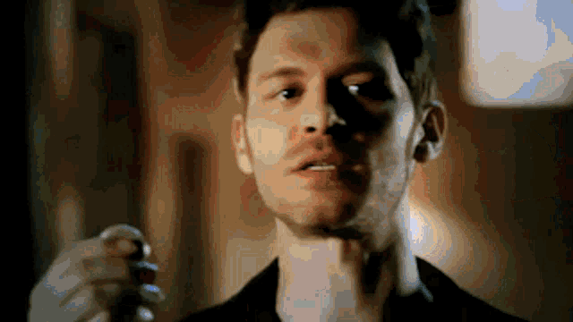 a man in a black shirt is holding a key in his hand and looking at the camera .