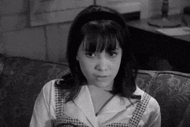 a black and white photo of a young girl sitting on a couch .