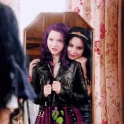two girls are standing next to each other in front of a mirror . one has purple hair and the other has black hair .