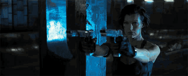a woman is pointing a gun at someone in a dark room .