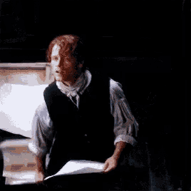 a man is holding a piece of paper in a dark room .