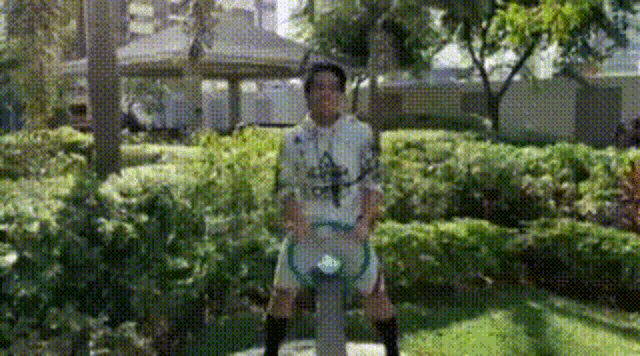 a man in a white shirt and black socks is standing in a park holding a hula hoop .