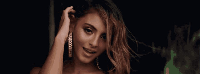 a woman wearing hoop earrings and a black top smiles