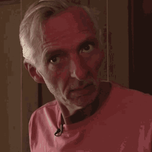 a man in a pink shirt is making a funny face with his mouth open