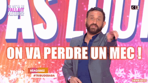 a man with a beard is pointing at something in front of a sign that says on va perdre un mec !