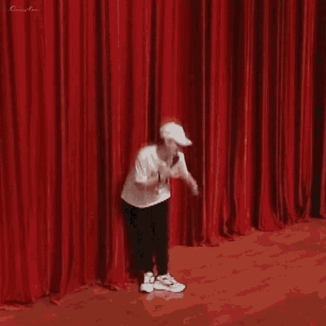a man is doing a handstand on a stage with red curtains .