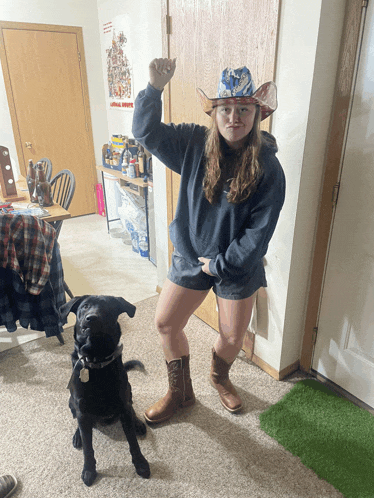 a woman in a cowboy hat stands next to a dog