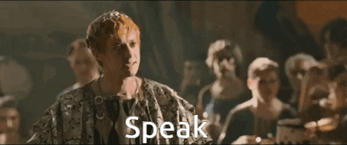 a man with a crown on his head is standing in front of a group of people and the word speak is above him
