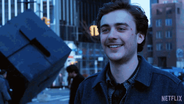 a young man is smiling in front of a netflix sign