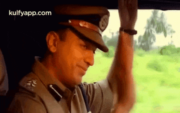 a man in a police uniform is sitting in a car and looking out the window .