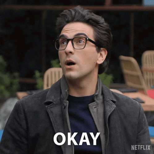 a man wearing glasses and a jacket with the word okay on his chest