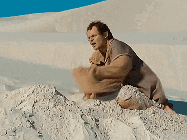 a man is sitting on a pile of sand and looking at the camera