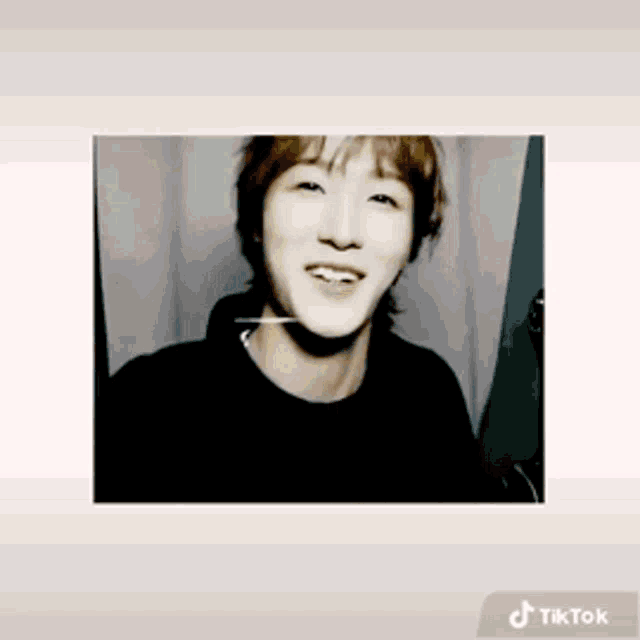 a young man is smiling in a black shirt with a tiktok icon next to him