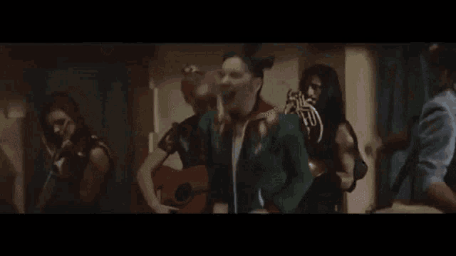 a group of people are standing next to each other playing instruments and singing .