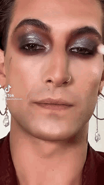 a close up of a man 's face with a nose ring and earrings .