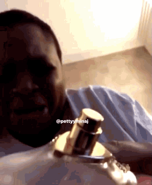 a man is holding a bottle of perfume and has the hashtag @pettyyminaj on his face